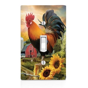 May include: A light switch cover featuring a rooster standing on a fence post with sunflowers in the foreground. The rooster is red, orange, and black with a long tail. The background is a painting of a red barn and a sunset.