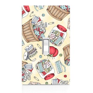 May include: A light switch cover with a yellow background and a repeating pattern of sewing supplies, including spools of thread, buttons, scissors, and jars of fabric scraps. The switch is labeled "OFF".