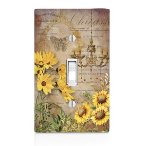 May include: A light switch cover with a vintage floral design featuring sunflowers, butterflies, and a chandelier. The background is a distressed, cream-colored paper with French text.