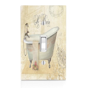 May include: A light switch cover with a vintage design featuring a white bathtub with gold accents, a towel, and the text "Le Bain" in a decorative font.