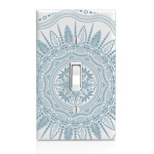 May include: A white light switch cover with a detailed blue mandala design. The switch is in the "OFF" position. The cover has a rectangular shape with rounded edges and a glossy finish. The design is symmetrical and features floral and geometric patterns.