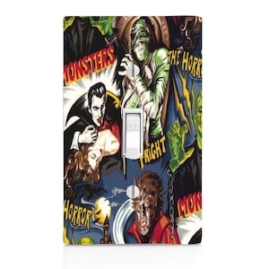 May include: A light switch cover featuring a colorful collage of vintage horror movie posters. The posters feature classic monsters like Dracula, Frankenstein's monster, and the Wolfman. The text on the posters includes "Monsters", "The Horror", "Fright", and "Horror".