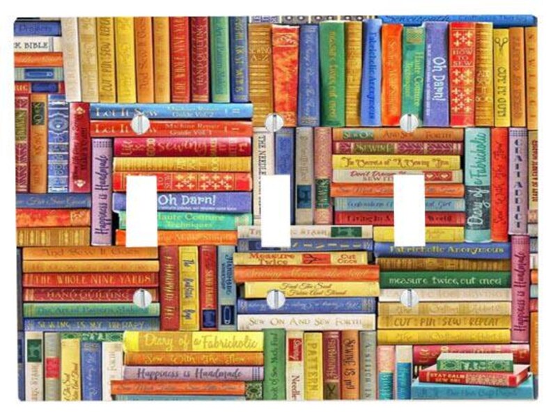May include: A triple light switch wall plate featuring a colourful, repeating pattern of book spines with various sewing-themed titles like 'Let It Sew', 'Oh Darn!', and 'Diary of a Fabricholic'. The rectangular plate has three vertical cutouts.