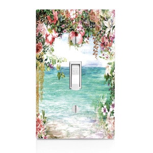 May include: A light switch cover with a watercolor design of a tropical beach scene with flowers and an ocean view. The switch is labeled "OFF".