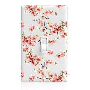 May include: White light switch cover with a pink and white floral pattern. The switch is labeled "OFF".