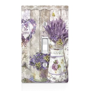 May include: A decorative light switch cover featuring a lavender theme. The design includes a wooden background, lavender bouquets in pitchers, and the text "Eau de Lavande". The color palette includes shades of purple, white, and beige.