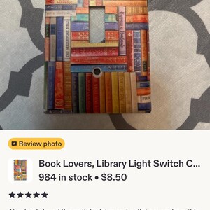 May include: A rectangular light switch cover plate featuring a colourful, multi-directional pattern of stacked book spines in various shades of red, blue, green, yellow, and orange. The plate has two screw holes and a central rectangular toggle cutout.