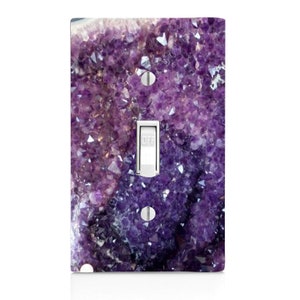May include: A light switch cover featuring a close-up image of a purple amethyst geode. The geode is filled with sparkling crystals.
