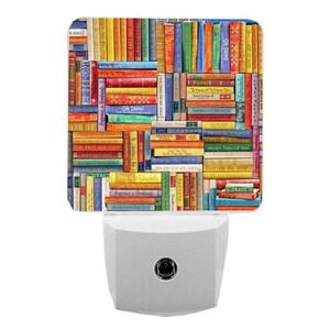 May include: A square night light featuring a colourful, multi-directional collage of book spines in various shades of red, blue, yellow, green, and orange. The design includes small text on several spines, set against a white plug-in base.