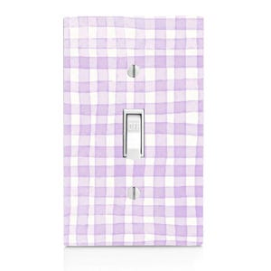 May include: A single-pole light switch cover with a watercolor-style gingham pattern in shades of lavender and white. The switch is white, with the word "OFF" printed on it. The cover has two silver screws.