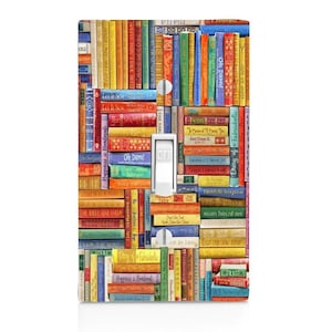 May include: A light switch cover with a colorful design of stacked books. The books have various titles, including "Happiness is Handmade", "Oh Darn!" and "The Fabulous."