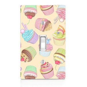 May include: A light switch cover with a pattern of colorful cupcakes on a light yellow background. The switch is labeled "OFF".