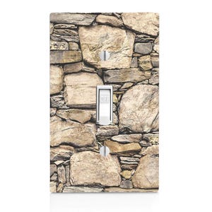 May include: A light switch cover with a stone wall design. The cover is made of durable plastic and features a realistic stone wall pattern. The switch cover is designed to fit standard light switches.