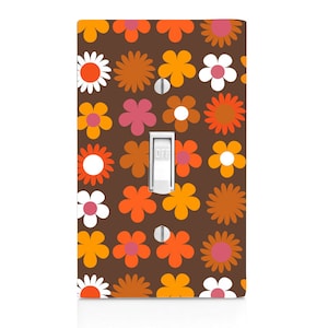 May include: A light switch cover with a brown background and a pattern of orange, pink, and white flowers. The switch is labeled "OFF".