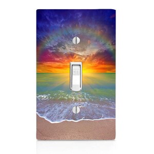 May include: A light switch cover with a beach sunset scene. The image shows a colorful sunset over the ocean with waves crashing on the sandy shore.