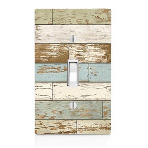 May include: A decorative light switch cover with a distressed wood plank design. The cover features a mix of colors including white, blue, brown, and green. The switch is white and reads "OFF".