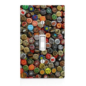 May include: A light switch cover with a colorful pattern of bottle caps. The caps are various colors, including red, blue, green, yellow, and brown. The caps have different logos and text, including "Abita!" and "Russian River".