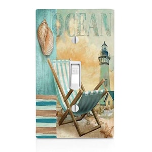 May include: A light switch cover with a beach scene featuring a lighthouse, a beach chair, and a seashell. The text "OCEAN" is printed on the cover.