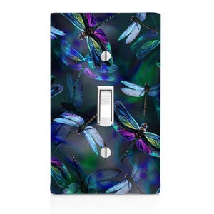 May include: A light switch cover with a design of blue and purple dragonflies on a dark blue background. The switch is labeled "OFF".
