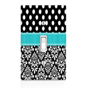 May include: A black and white light switch cover with a turquoise ribbon and a polka dot pattern on the top half and a damask pattern on the bottom half. The switch cover has the word "OFF" printed on it.