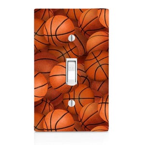 May include: A light switch cover with a pattern of orange basketballs.
