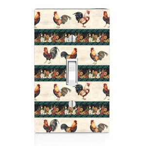 May include: A light switch cover with a pattern of roosters and floral borders. The cover is white with a beige background and features a light switch with the word "OFF" printed on it.