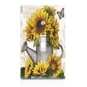 May include: A light switch cover featuring a vintage-style illustration of sunflowers, a watering can, and a butterfly. The switch is labeled "OFF".