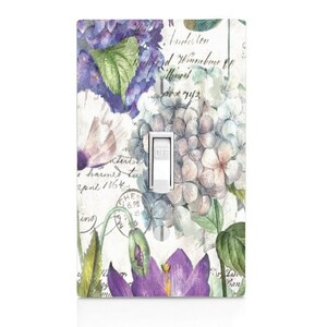 May include: Light switch cover with a floral design featuring purple, blue, and white hydrangeas, green leaves, and handwritten text. The switch is labeled "OFF".