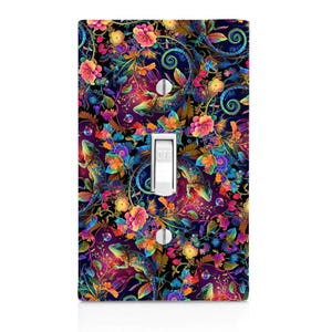 May include: A light switch cover with a colorful design featuring lizards, flowers, and swirls. The background is dark blue with vibrant pink, purple, green, and yellow accents.