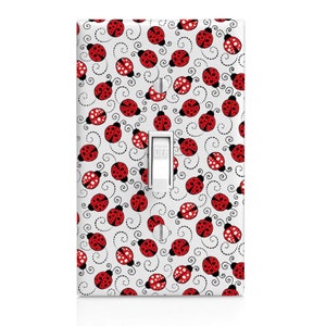 May include: White light switch cover with a red and black ladybug pattern. The switch is labeled "OFF".