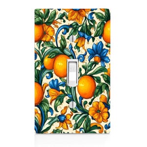 May include: A decorative light switch cover featuring a vibrant floral design with oranges, blue flowers, and yellow blossoms. The switch is white, with the word "OFF" printed on it. The background is a cream color.