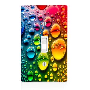 May include: A decorative light switch cover featuring a vibrant, colorful design of water droplets. The droplets are in shades of blue, green, yellow, orange, and red. The switch is white and in the "off" position.