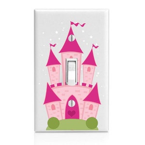 May include: Pink castle light switch cover with a white light switch and the word "OFF" on it. The castle has a heart-shaped door and is surrounded by green grass and bushes.