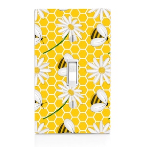 May include: A yellow light switch cover with a honeycomb pattern, white daisies, and black and yellow bees. The switch is labeled "OFF".
