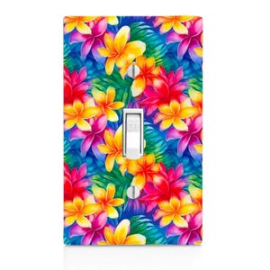 May include: A rectangular light switch cover plate featuring a vibrant tropical pattern of yellow, orange, and magenta plumeria flowers interspersed with green palm leaves on a deep blue background. The white toggle switch has the word OFF printed.