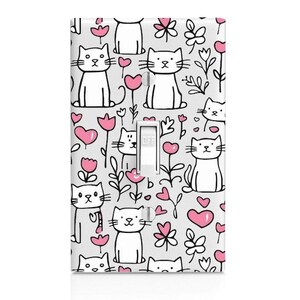 May include: A rectangular light switch wall plate featuring a repeating pattern of white cartoon cats with black outlines, pink heart shapes, and black line-drawn flowers on a light gray background, with a white toggle switch in the center.