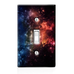 May include: A light switch cover with a galaxy design. The cover features a dark background with swirling colors of red, orange, blue, and purple. The switch is labeled "OFF".