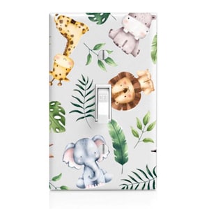 May include: A light switch cover with a white background and a pattern of jungle animals, including a giraffe, elephant, hippopotamus, and lion. The animals are drawn in a watercolor style and are surrounded by green leaves. The switch is labeled "OFF".