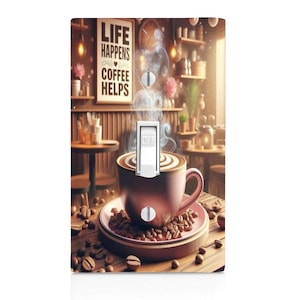 May include: A light switch cover with a design of a steaming cup of coffee with the text "Life Happens Coffee Helps" on a sign behind it.