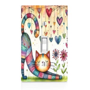 May include: A decorative light switch cover featuring a colorful cat stretching towards the viewer. The cat's body is a patchwork of colors, with a rainbow tail and a striped head. The background includes hanging hearts and flowers.
