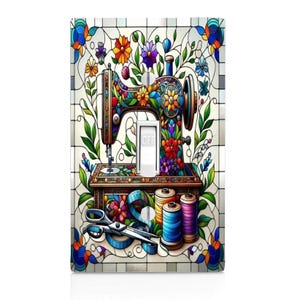 May include: A colorful light switch cover featuring a vintage sewing machine design. The artwork includes floral accents, spools of thread, scissors, and a measuring tape. The switch is in the "OFF" position.