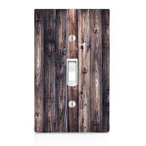May include: A decorative light switch cover featuring a wood grain design. The cover has a white toggle switch in the center with the word "OFF" printed on it. Two silver screws are visible above and below the switch.