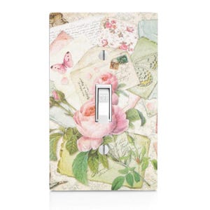 May include: A light switch cover with a vintage floral design featuring pink roses, green leaves, and a butterfly on a background of old letters and envelopes.
