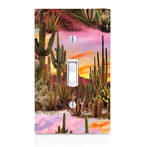 May include: Light switch cover with a colorful desert sunset scene featuring a variety of cacti and succulents. The background is a gradient of pink, orange, and yellow.