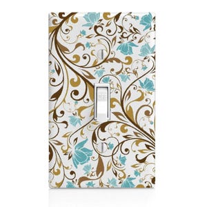 May include: A decorative light switch cover with a white background and a floral pattern. The design features brown, gold, and teal blue flowers and vines. The switch is in the "OFF" position.