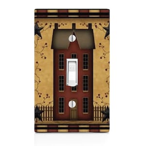 May include: A light switch cover with a decorative design of a red house with a brown roof and white windows. The house is surrounded by a fence and vines with black stars. The switch is labeled "OFF".