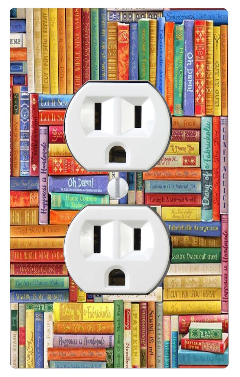 May include: A rectangular wall plate for a double electrical outlet featuring a colourful print of stacked books with sewing-themed titles like Oh Darn, Sew With The Flow, and Happiness is Handmade, with two white plastic sockets.
