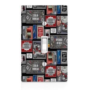 May include: A decorative light switch cover with a black background featuring motorcycle-themed graphics. The design includes images of motorcycles, tools, and the text "My Garage My Rules" and "One Rule Don't Touch My Stuff!"