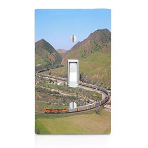 May include: A light switch cover featuring a scenic landscape with a train winding through green hills under a blue sky. The switch is white with the word "OFF" printed on it.
