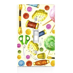 May include: A light switch cover with a colorful pattern of sewing supplies, including spools of thread, buttons, scissors, needles, and yarn. The switch is labeled "OFF".